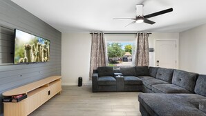 A modern living room with a flat-screen TV, grey sectional sofa, and a wooden entertainment unit. - Minutes from Old Town Scottsdale with pool. Dual Primary BDRS. (Scottsdale)