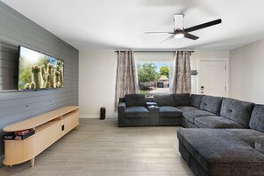A modern living room with a flat-screen TV, grey sectional sofa, and a wooden entertainment unit. - Minutes from Old Town Scottsdale with pool. Dual Primary BDRS. (Scottsdale)