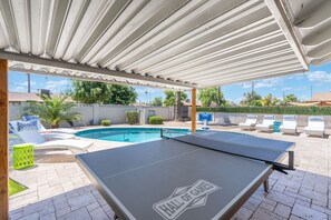 An outdoor pool area with a ping pong table, lounge chairs, and a covered seating area. - Heated Pool! Minutes from Old Town Scottsdale. Dual Primary BDRS. (Scottsdale)