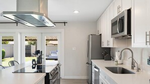 A modern kitchen with white cabinetry, stainless steel appliances, and a large island with a sink. - Minutes from Old Town Scottsdale with pool. Dual Primary BDRS. (Scottsdale)