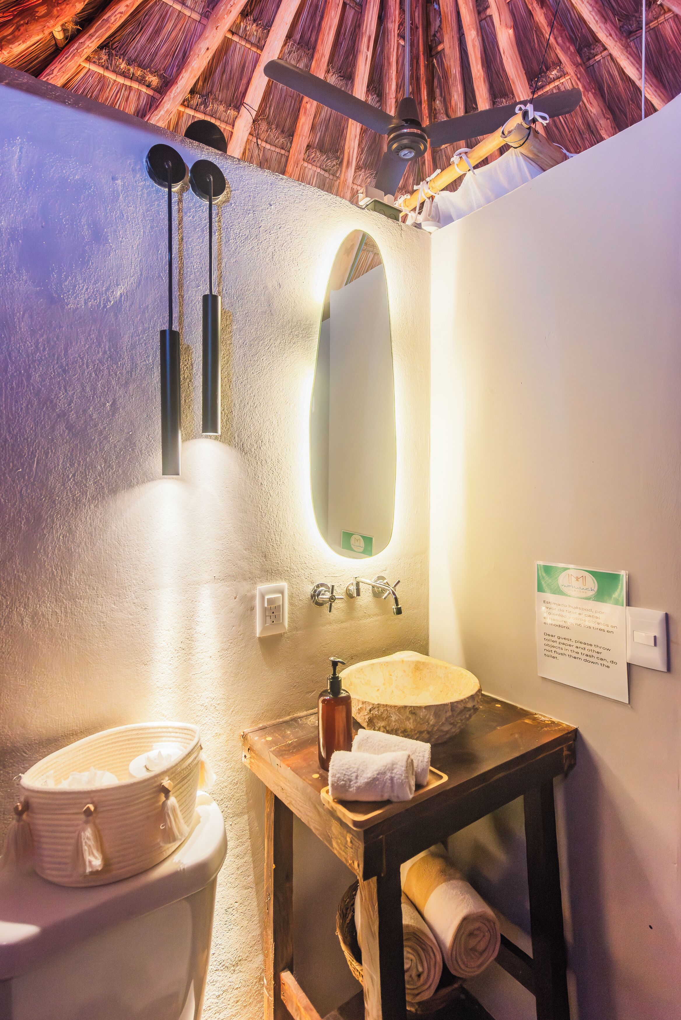 A bathroom with a wooden ceiling, a white sink, a mirror, and a towel rack.