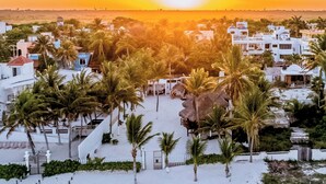 Une zone côtière avec des bâtiments blancs, des palmiers et un coucher de soleil.