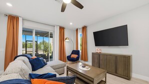 Ein modernes Wohnzimmer mit einer Couch, einem Sessel, einem Couchtisch und einem an der Wand befestigten Fernseher.