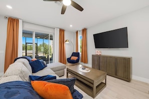 Ein modernes Wohnzimmer mit einer Couch, einem Sessel, einem Couchtisch und einem an der Wand befestigten Fernseher.