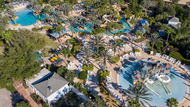 Eine Luftaufnahme eines Resorts mit mehreren Swimmingpools, Palmen und Liegebereichen.