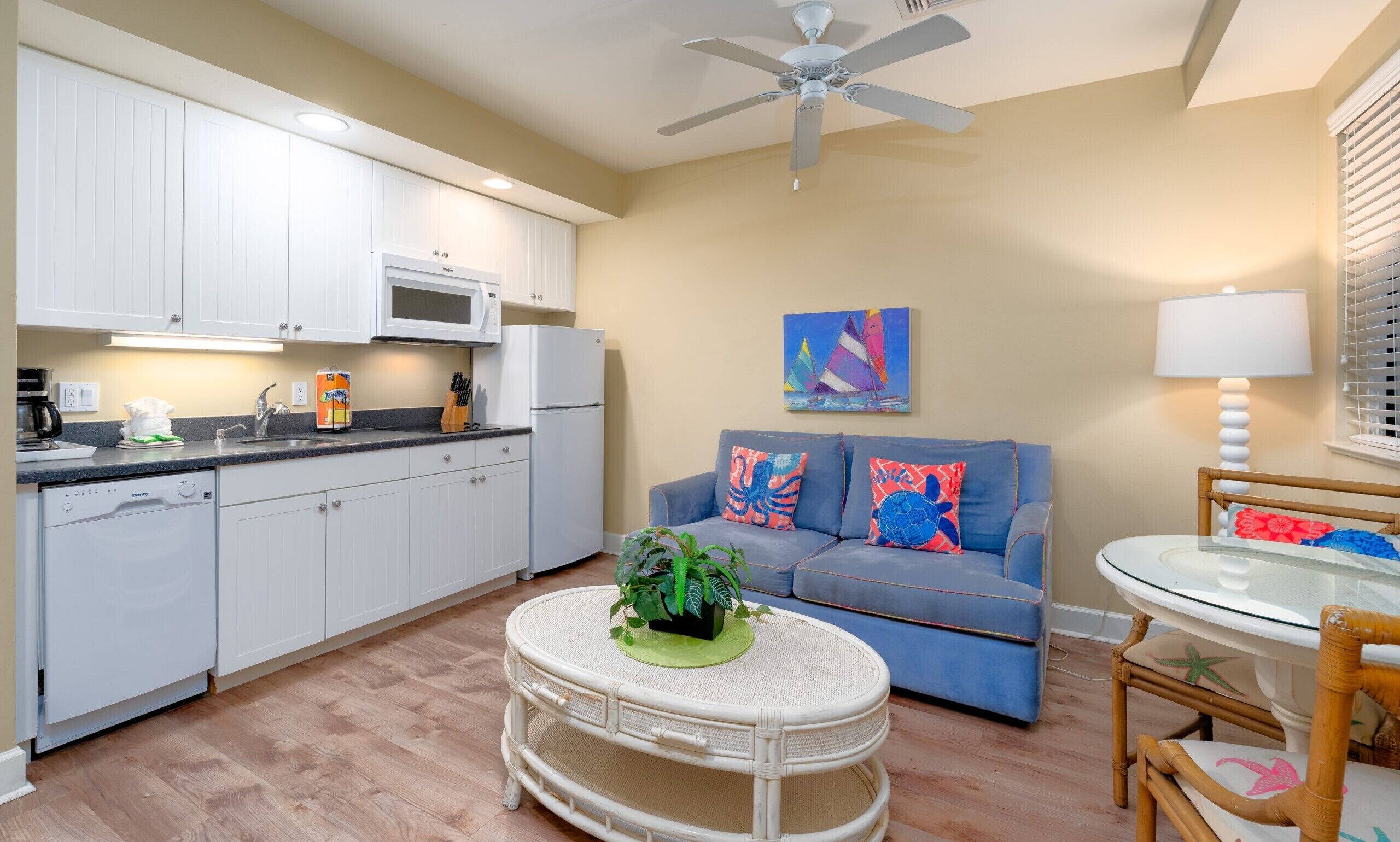 A compact living space with a kitchenette, a dining area, and a seating area with a ceiling fan.