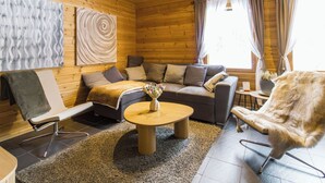A cozy log cabin interior with a sofa, armchair, and a round coffee table. - Mökki maui by Interhome (Pelkosenniemi)