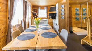 A wooden interior with a dining table set for four, a kitchen area, and a staircase. - Mökki maui by Interhome (Pelkosenniemi)