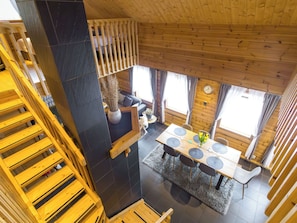 A wooden interior with a dining area, a staircase, and a view of the outside.