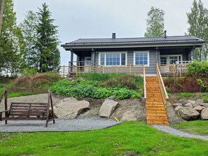 A house with a wooden deck, a ramp, and a bench.