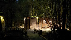 A rustic wooden structure with a sign, surrounded by trees and a gravel path.