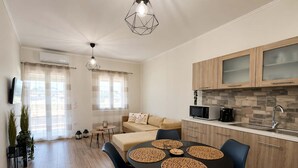 A modern kitchen with wooden cabinets, a microwave, and a sink. There is a dining area with a table and chairs. - Casa Plati 1 2 - Private Pool Garden Stay (Kalamata)