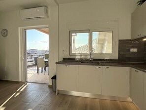 A modern kitchen with a window, white cabinets, and a view of the city.