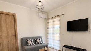 Un salon moderne comprenant un canapé, une table basse, un banc et un téléviseur à écran plat fixé au mur.