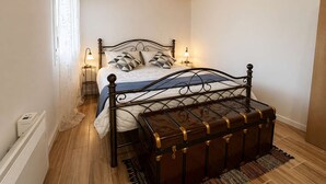 A bedroom with a wooden ceiling, a metal bed frame, a bedside table with a lamp, and a suitcase on the floor. - Casa Plati 1 - Modern Escape With Pool Garden (Kalamata)
