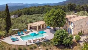 A villa with a swimming pool, outdoor seating, and a view of the surrounding hills. - Villa La Bergerie by Villa Plus (Saint-Cézaire-sur-Siagne)