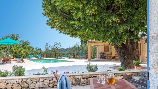 A poolside area with lounge chairs, a table with drinks, and a stone wall. - Villa La Bergerie by Villa Plus (Saint-Cézaire-sur-Siagne)