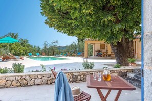 Ein Poolbereich mit Liegestühlen, einem Tisch mit Getränken und einer Steinmauer.