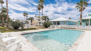 A swimming pool with white chairs, palm trees, and a clear sky.