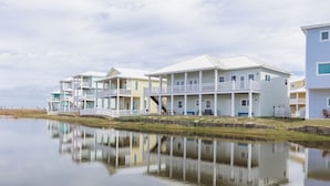 A waterfront property with multiple-story houses, a dock, and a calm body of water reflecting the buildings.