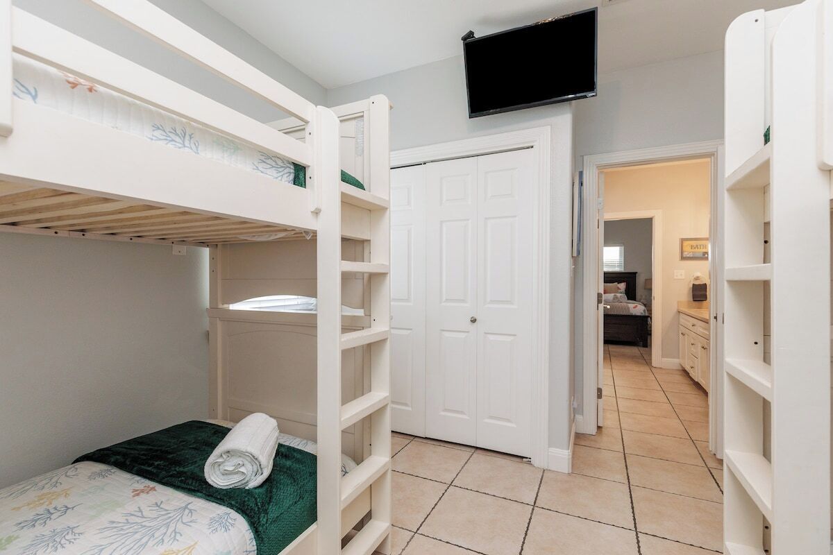 Une chambre avec des lits superposés, une télévision, un placard et, au fond, une salle de bain.