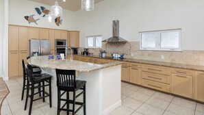 A kitchen with a large island, wooden cabinets, stainless steel appliances, and decorative wall art.
