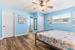 A bedroom with a bed, a ceiling fan, and a window with blinds.