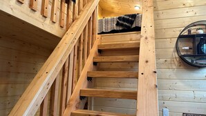 Eine Holztreppe mit Handlauf, ein an der Wand befestigter Spiegel und ein Schild, das Ausflüge zum Angeln anzeigt.