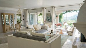 Ein geräumiger Wohnbereich mit Sofa, Stühlen, einem Esstisch und Blick ins Freie.