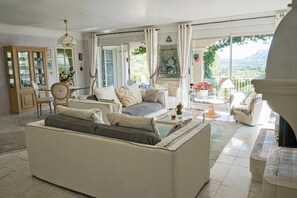 Ein geräumiger Wohnbereich mit Sofa, Stühlen, einem Esstisch und Blick ins Freie.