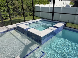 Ein rechteckiges Whirlpool mit Fliesenrand, umgeben von einem Pool.