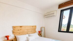 Una camera da letto con una testiera in legno, un letto grande con biancheria da letto bianca, una coperta azzurra e una finestra con vista.