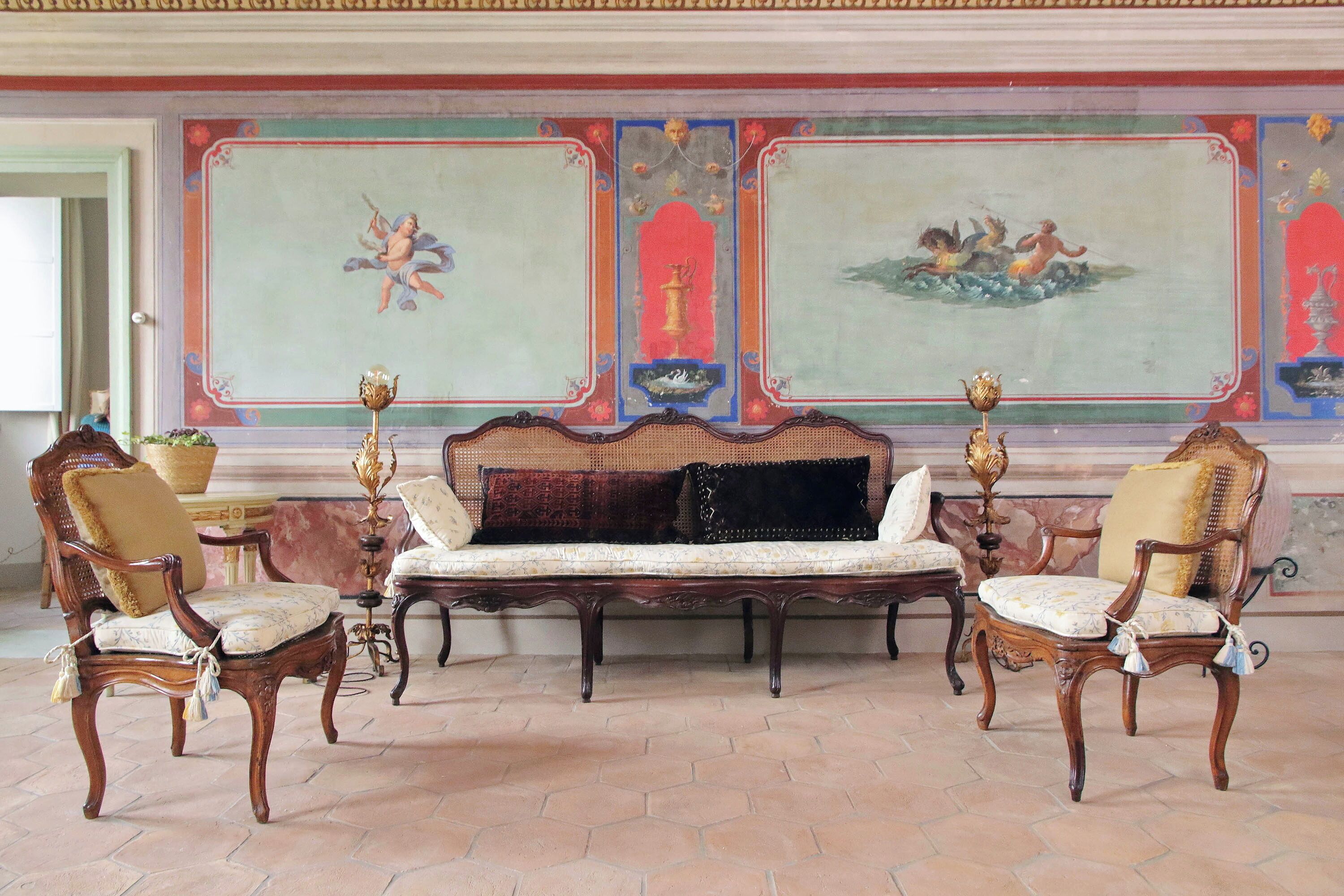 Ein Zimmer mit einer großen Wandmalerei, einem Sofa und zwei Sesseln.
