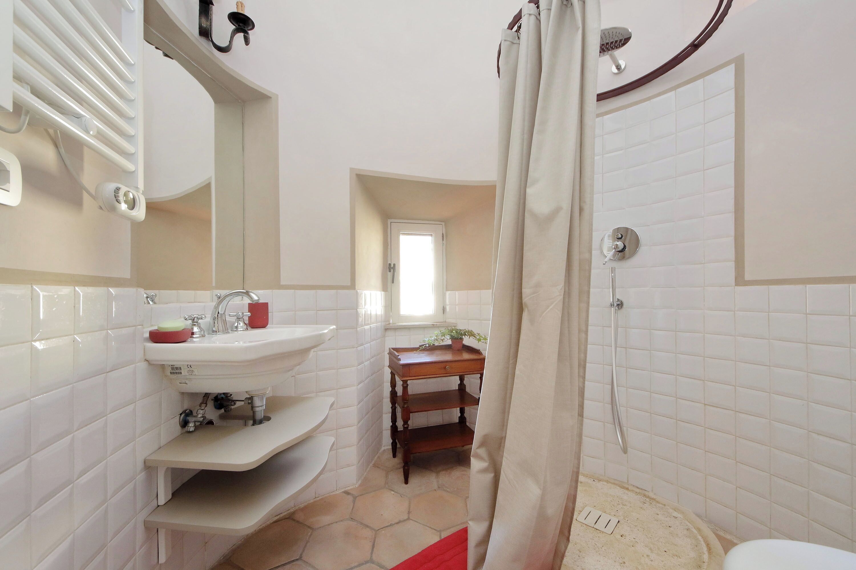 A bathroom with a white sink, mirror, and shower.