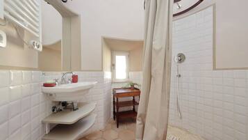 A bathroom with a white sink, mirror, and shower.