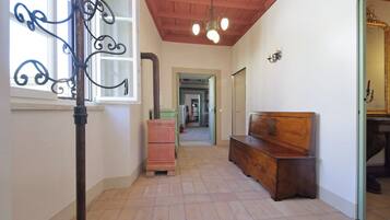 Un couloir avec un banc en bois, un poteau en métal et un miroir.