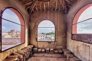Un interior con ventanas de arco, piso de concreto y pilas de objetos planos.