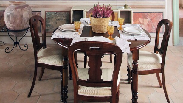 A dining area with a table set for four, surrounded by wooden chairs with woven seats.
