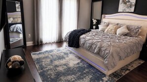 Une chambre à coucher moderne, avec un lit, un ventilateur de plafond, une table de chevet et une grande fenêtre avec des rideaux.