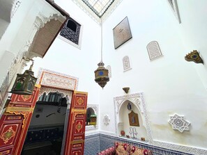 A room with ornate white and red doors, a hanging lantern, and intricate wall decorations.