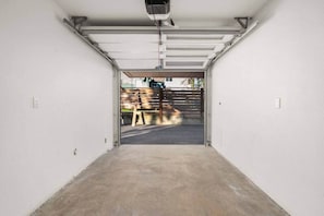 A garage with a concrete floor and a metal door. - Brand New 3BR Townhome - Near Light Rail and Airport (Seattle)