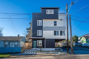 A modern two-story residential building with a flat roof, a garage, and a visible driveway. - Brand New 3BR Townhome - Near Light Rail and Airport (Seattle)
