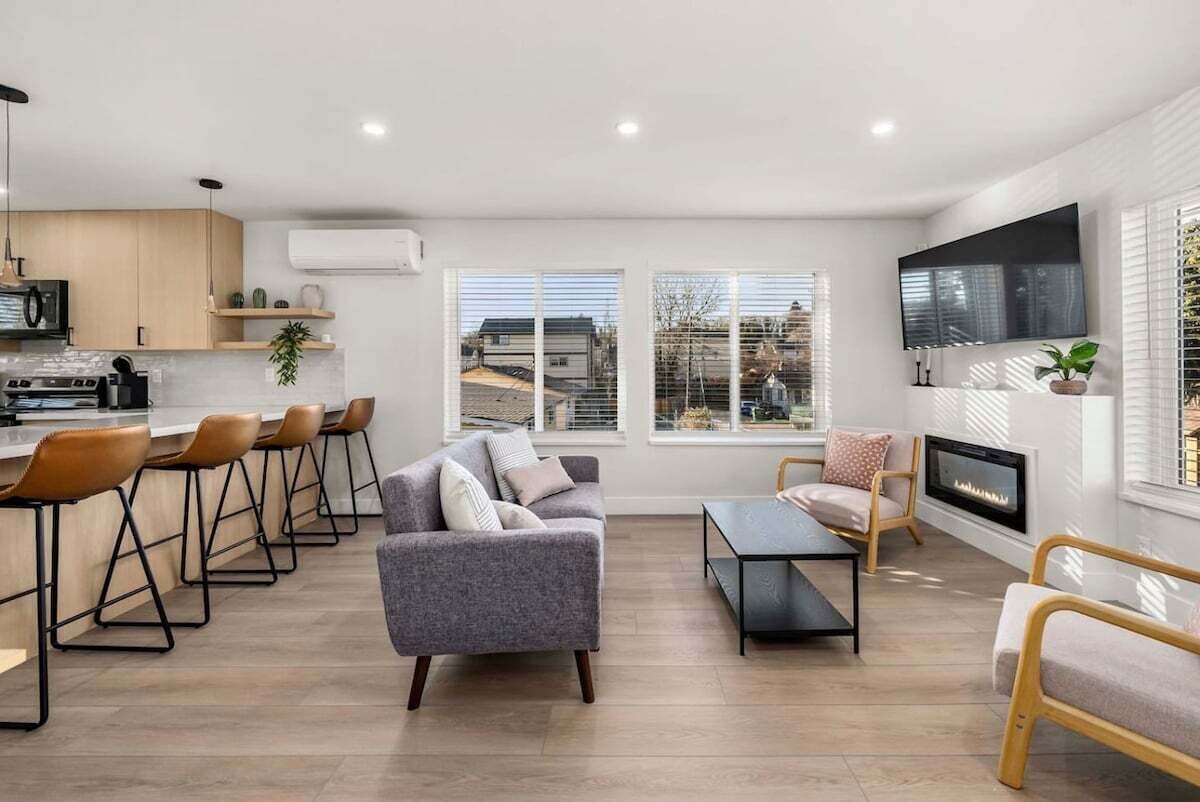 A modern living room with a sofa, chairs, a fireplace, and a TV.