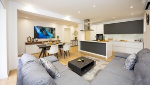 Ein modernes Wohnzimmer mit einer Sofagarnitur, einem Couchtisch und einem Fernseher.