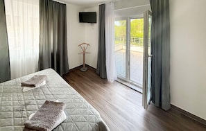 A hotel room with a bed, a chair, a TV, and a sliding glass door to the outside. - Stunning home in Donji Prolozac (Donji Prolozac)