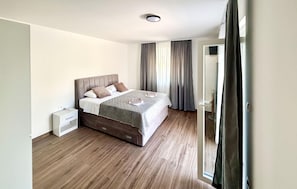 A bedroom with a bed, bedside tables, a wardrobe, and a window with curtains. - Stunning home in Donji Prolozac (Donji Prolozac)