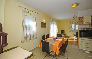 A dining area with a table, chairs, a television, and kitchen appliances. - Lovely home in Kresevo (Kresevo)