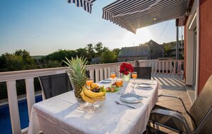 A dining table set on a balcony with a pool view, fruit bowl, and drinks. - Lovely home in Kresevo (Kresevo)