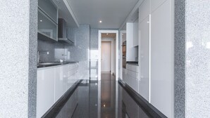 A modern kitchen with granite countertops, white cabinetry, and a sleek, reflective floor. - La Belle Vie by Atlantic Holiday (Funchal)