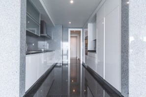 A modern kitchen with granite countertops, white cabinetry, and a sleek, reflective floor. - La Belle Vie by Atlantic Holiday (Funchal)